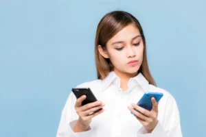 2つのスマホを見比べる女性