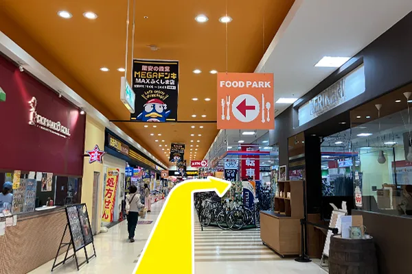 入店し真っ直ぐ進むと、ATMの案内看板がございますので、そちらを右に曲がります。