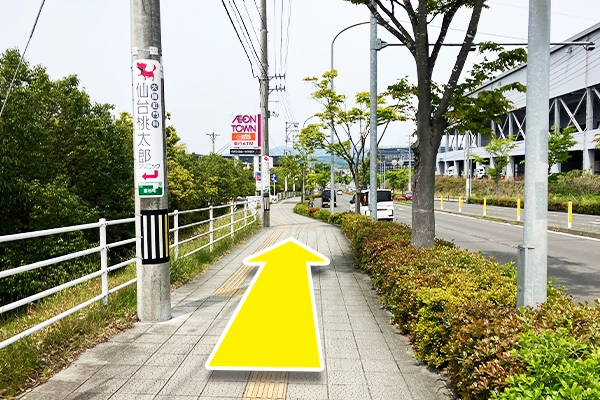 横断歩道を渡るとイオンタウンの看板があります。坂を下り敷地内に入ります。