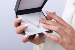 ネックレスを持つ女性の手元