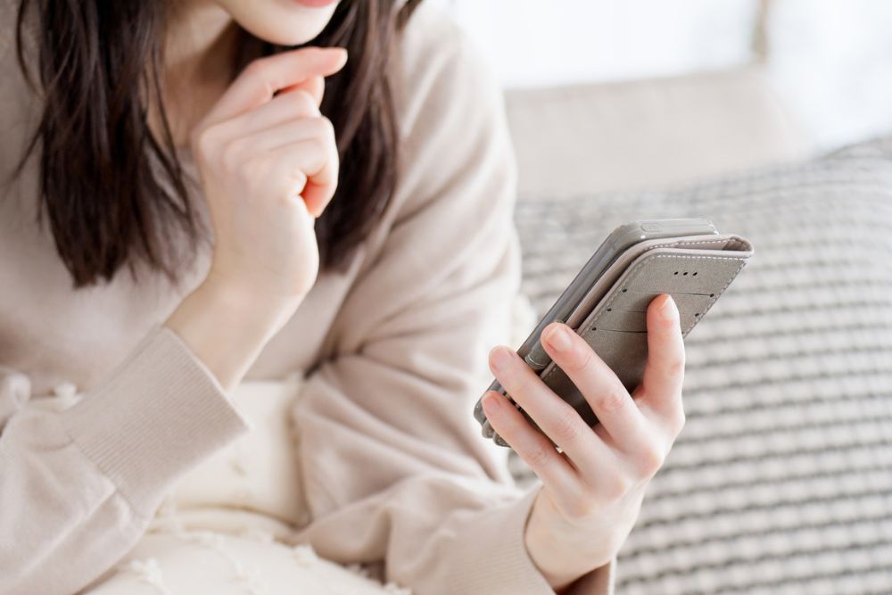 スマホを見ながら悩む女性