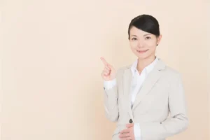 人差し指を立てるスーツの女性