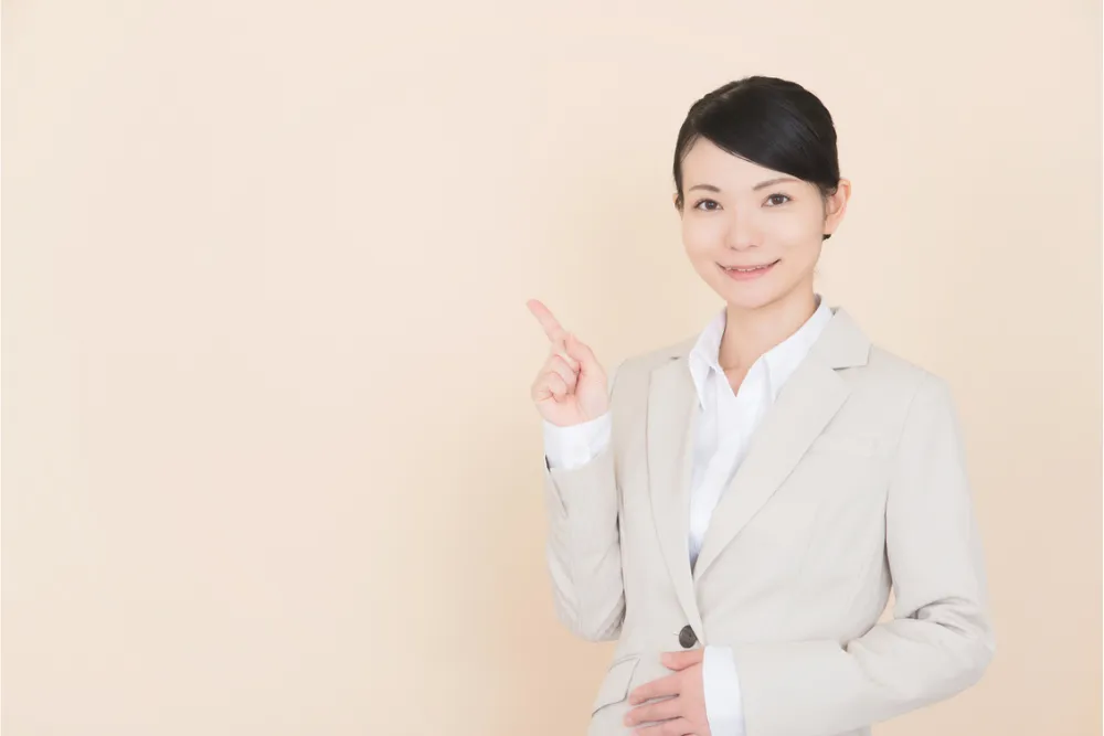人差し指を立てるスーツの女性