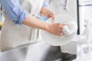 皿洗いをするシャツを着た女性