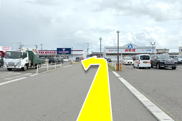 真っ直ぐ進んで頂き、左側の施設の赤い自動販売機の前を左に曲がってください。